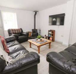 A living room with a wooden coffee table and television at Cariad Cottage in Cross Inn