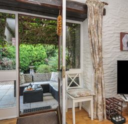 A living room with door and view of garden at Wagtail Cottage in East Taphouse