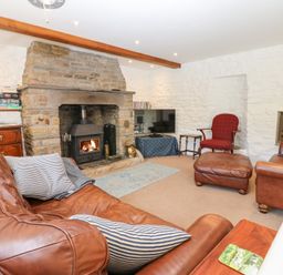 A living room with leather sofas fireplace and a television at Farrier's Cottage in Garsdale