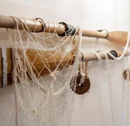 A pair of wooden oars with fishing nets hanging on a wall at Nectan in Mevagissey