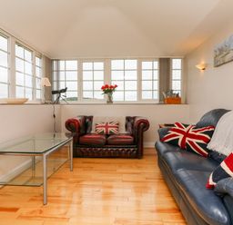 A living room with two leather sofas and a glass coffee table at The Well House Apartment in Watchet