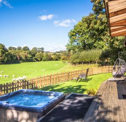 An outdoor space with a hot tub and seating area at Sycamore Lodge Nantmel near Rhayader