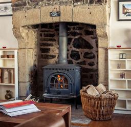 A living room with a fireplace wood stove and bookshelves at Bastle House in Haltwhistle near Hadrians Wall