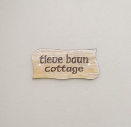 A wooden sign with text tieve baun cottage mounted on a plain wall at Tieve Baun in Ballintrillick near Kinlough County Sligo