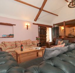 A living room with sofas a wooden coffee table and bookshelf with board games at The Barn in Bicknoller