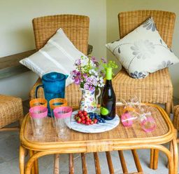 A seating area with wicker chairs cushions a table with fruit glasses a pitcher and a bottle at The Old Mill in Dolau near Llandrindod Wells