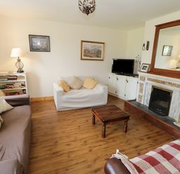 A living room with sofas a wooden coffee table a fireplace and a television at Lough Mask Road Fishing Lodge in Ballinrobe County Mayo
