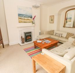A living room with two cream sofas a wooden coffee table a fireplace and a large mirror at Berlin House in Tenby