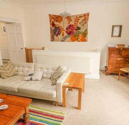 A living room with a white sofa a wooden coffee table a striped rug and a wooden desk at Berlin House in Tenby