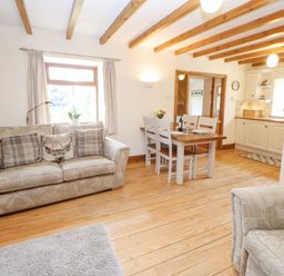 A living room with a sofa a dining table and chairs and a kitchen at The Barn Cottage Steel near Hexham