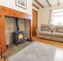 A living room with a fireplace wood stove sofa and wooden floor at The Barn Cottage Steel near Hexham