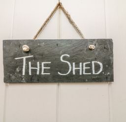 A hanging slate sign with the text The Shed on a white wall at The Potting Shed in Burton-in-Kendal near Kirkby Lonsdale