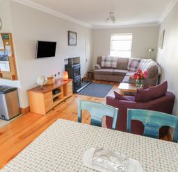 A living room with a sofa armchair and wooden cabinet with a globe and a television at Teach Teolai in Carraroe County Galway