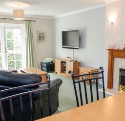 A living room with leather sofas wooden coffee table and TV mounted on wall at Treetops in Rhos-On-Sea