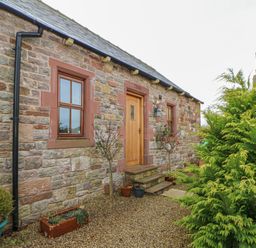 Stone house exterior with wooden door and windows gravel pathway and potted plants at Swallow Cottage in Milton near Brampton