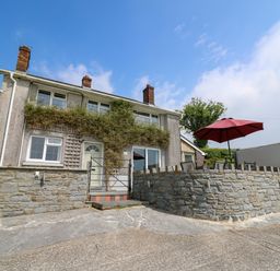 A two story house with stone walls and red umbrella on patio at Aberdauddwr in Lampeter