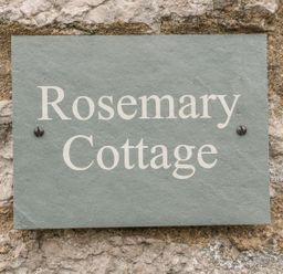 A sign reading Rosemary Cottage mounted on a stone wall at Rosemary Cottage in Clawthorpe near Burton-in-Kendal