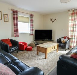 A living room with sofa and coffee table at Ty Ni Caeathro near Caernarfon