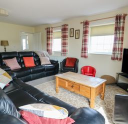 A living room with leather sofas and a wooden coffee table at Ty Ni in Caeathro near Caernarfon
