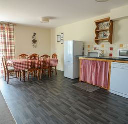 A kitchen with dining table and appliances at Ty Ni in Caeathro near Caernarfon