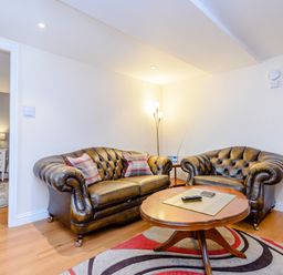 A living room with two leather sofas a wooden coffee table and a patterned rug at Mermaid Cottage in Whitby
