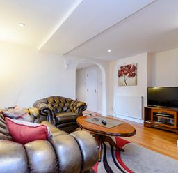 A living room with leather sofas a wooden coffee table a TV on a wooden stand and a floor lamp at Mermaid Cottage in Whitby
