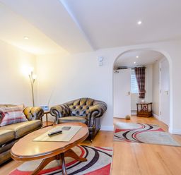 A living room with leather sofas a wooden coffee table a floor lamp and patterned rugs at Mermaid Cottage in Whitby
