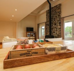 A kitchen table with eggs, lemon biscuits, and tea bags with a living room and stone fireplace in the background at Meader Barn in Peter Tavy near Tavistock