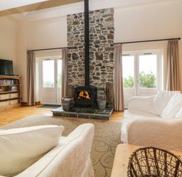 A living room with a stone fireplace flanked by two doors and white sofas with cushions at Meader Barn Peter Tavy near Tavistock