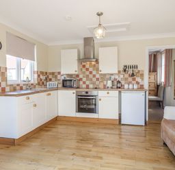A kitchen with white cabinets wooden countertops and tiled backsplash at Norbank Garden Studio in Bressingham