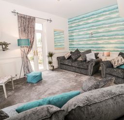 A living room with grey sofas and blue pillows a patterned wall and a floor lamp at St Cuthberts Cottage in Beal near Holy Island