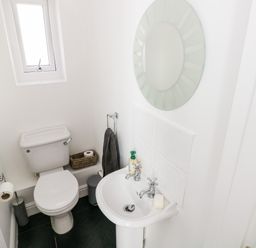 A small bathroom with a toilet sink mirror and window at 1 Atlantic Haven in Llangennith