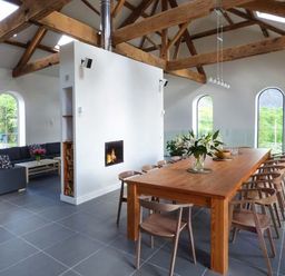 An open living and dining area with a wooden dining table and chairs a fireplace and a sectional sofa at Capel Dinorwig in Llanberis