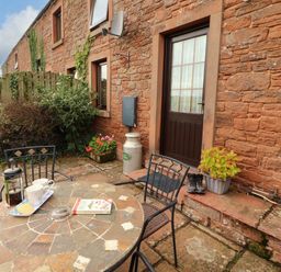 An outdoor seating area with a table and a door at Stable Cottage in Bolton Low Houses
