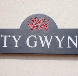 A nameplate with TY GWYN and a dragon crest at Ty Gwyn in Llangwm near Bala