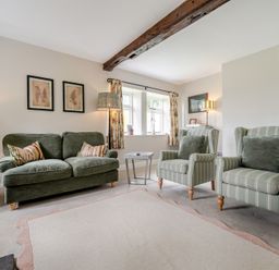 A living room with a sofa, armchairs, and a table at Dove Cottage at the Graythwaite Estate near Hawkshead