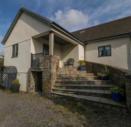 Entrance of a house with stone steps and potted plants at Nant-yr-Rhedyn in Red Wharf Bay