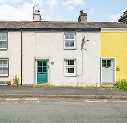 A row of three adjoining cottages with different colored doors and walls on a roadside at No 7 Spark Bridge near Ulverston