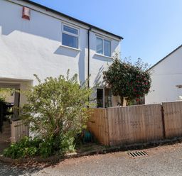 A white two-story house with a wooden fence a garden hose and a small tree at Moorside in Horrabridge near Tavistock