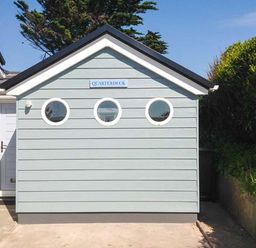 The exterior of a building with three round windows and a sign that says Quarterdeck at Bigbury-on-Sea near Modbury