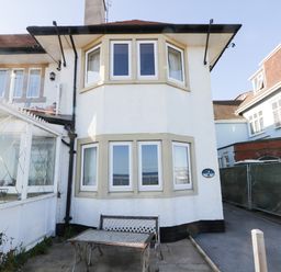 A white house exterior with bay windows and metal table and bench on the patio at Seascape in Bridlington