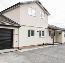 The exterior of a two story house with a garage and multiple windows at Bryn Derw Holiday Cottage in Eglwysbach near Llanrwst and Conwy