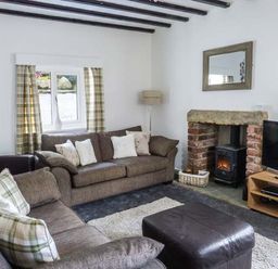 A living room with two sofas a window with curtains a fireplace and a television at The Nook in Bowness-On-Windermere