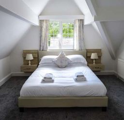 A bedroom with a bed towels and bedside lamps under a window at The Nook in Bowness-On-Windermere