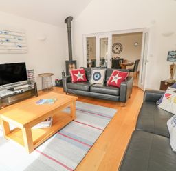 A living room with two black leather sofas a wooden coffee table and a flat screen tv at Atlantic Reach in Widemouth Bay