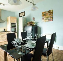 A kitchen with a black dining table set with plates and glasses with black chairs at Westgate Retreat in Hunstanton