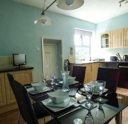 A kitchen with a black dining table set with bowls and glasses and light wood cabinets at Westgate Retreat in Hunstanton