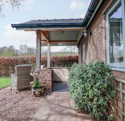 An outdoor porch with a chair and plants at The Lodge, Lower Trefedw near Abergavenny