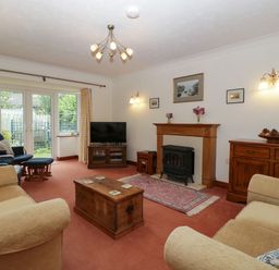 A living room with sofas armchairs a wooden chest a television a fireplace and glass doors at Hurst Green in Ewyas Harold near Hereford