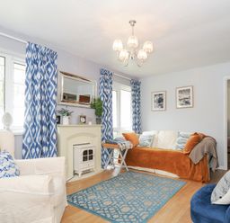 A living room with armchairs sofa a rug and blue patterned curtains at No 1 The Heathers Rosecraddoc Lodge near Liskeard